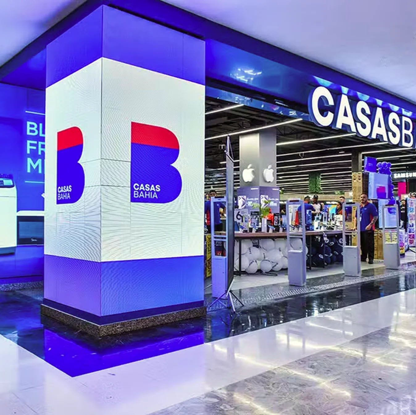 Fachada iluminada de uma loja Casas Bahia com o totem da marca em destaque