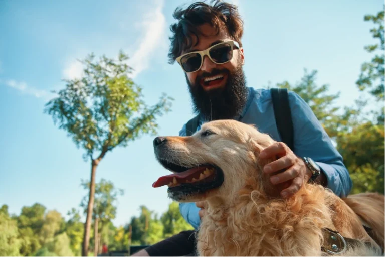 Homem de óculos escuros acariciando um cachorro golden retriever